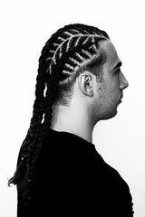 Attractive guy with braids posing in studio on isolated background. Style, trends, fashion concept.