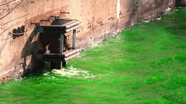 Green water splashes against a concrete wall and pipes along the Chicago River after the city and plumber's union dyed the water green for St. Patrick's Day holiday.