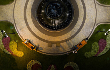 Green park with round fountain, people on the benches. View from above.