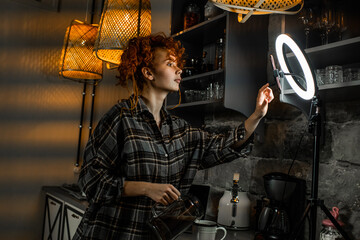 Female blogger with ring light and smartphone records video for social media in a kitchen. Blogger...