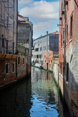 Fototapeta na wymiar Narrow canal in Venice, Italy with colourful buildings around . cloudy day