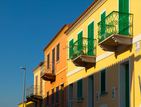 Yellow house facade with balconies and green window shutters, Sardinia, Italy