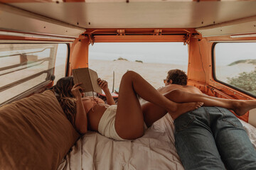Young surfing couple lying in back of recreational vehicle at beach, Jalama, California, USA