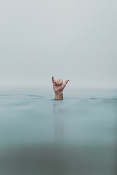 Male scuba diver's hand signalling decompression from sea, Ventura, California, USA