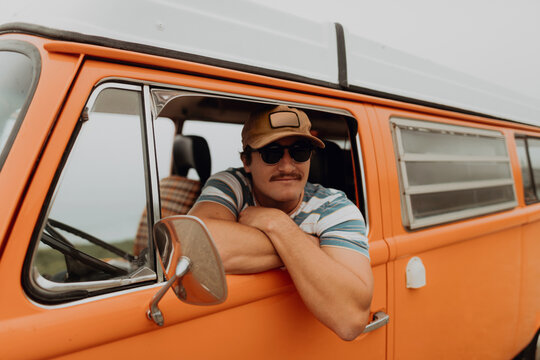 Young man leaning out of recreational vehicle window,  portrait, Jalama, California, USA