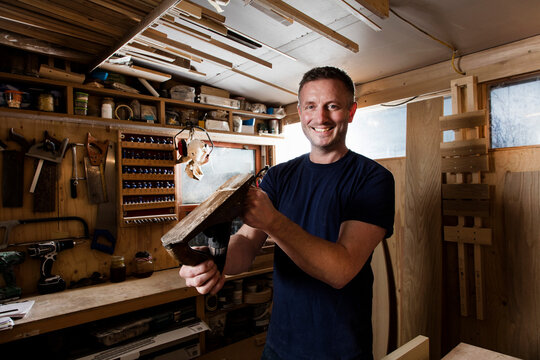 Craftsman holding wood plane in workshop