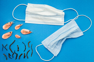 Application on ocean pollution after the consequences of the covid 19 pandemic. Shrimp and algae are suffering from used masks, gloves and plastic and other waste against a blue background.