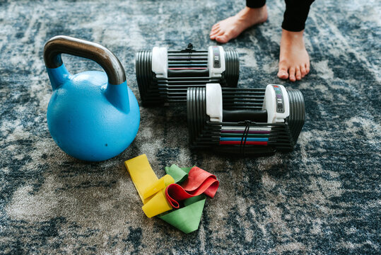 Kettle bell and assortment of exercise equipment by pair of feet