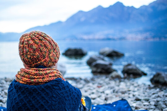 Boy sitting on blanket on lakeside, rear view, Lake Como, Onno, Lombardy, Italy