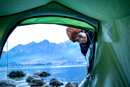 Boy peering into tent by lakeside, Onno, Lombardy, Italy