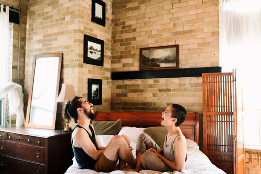 Couple sitting cross legged laughing on bed
