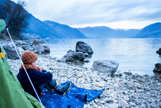 Boy sitting outside tent on lakeside, Lake Como, Onno, Lombardy, Italy