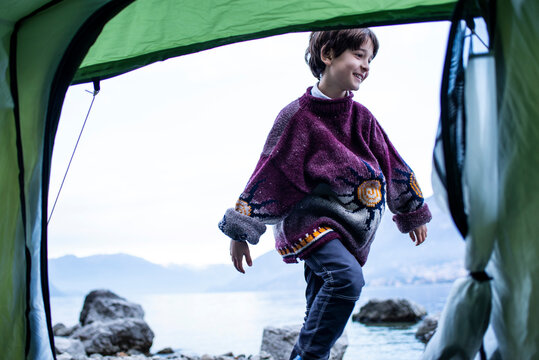 Boy playing outside tent on lakeside, Lake Como, Onno, Lombardy, Italy