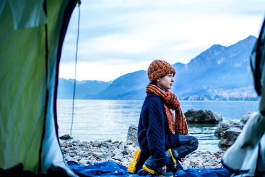 Boy outside tent on lakeside, Lake Como, Onno, Lombardy, Italy