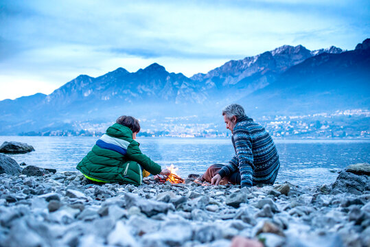Father and son starting campfire, Onno, Lombardy, Italy