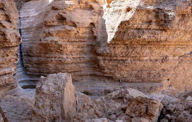 Female hiker on a hiking trail in a remote region of the nature reserve in the Negev Desert. Panoramic landscape of limestone mountains. High walls of a narrow canyon. Huge boulders.