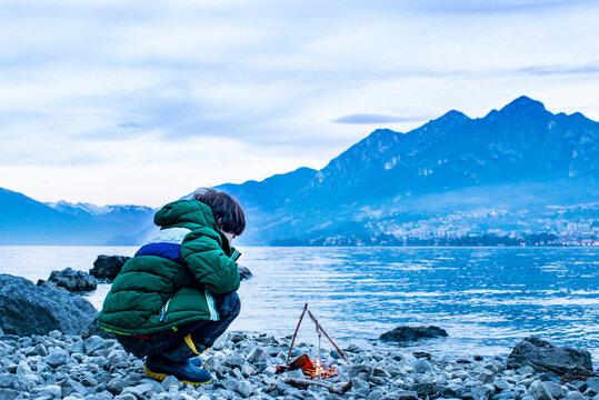 Boy by campfire at dusk, Onno, Lombardy, Italy