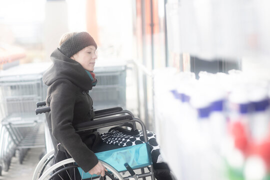 Woman in wheelchair going into supermarket