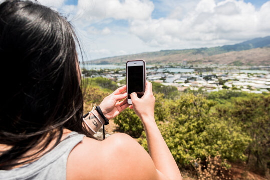 Hiker taking photograph of town of Halona Beach, Oahu, Hawaii