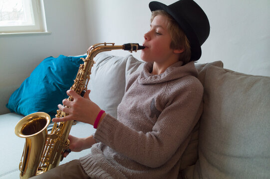 Boy practising saxophone on sofa