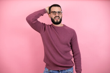 Handsome man wearing glasses and casual clothes over pink background putting one hand on her head smiling like he has forgotten something
