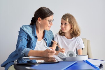 Mom and daughter student learning school lessons together at home