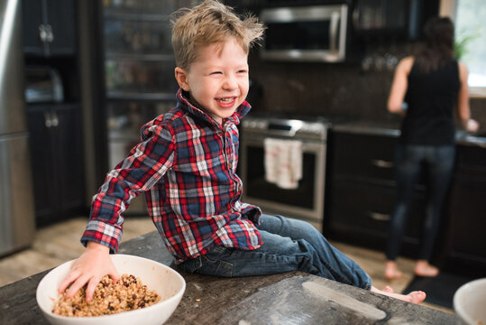 Toddler grabbing freshly baked vegetarian seed balls from bowl on kitchen worktop