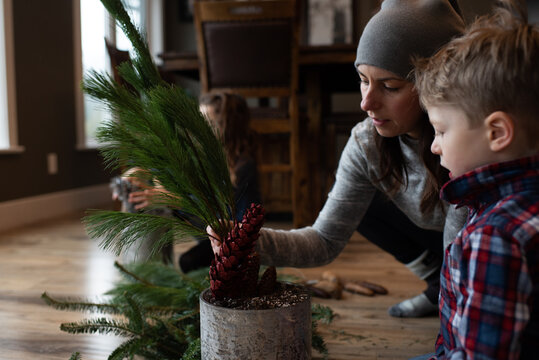 Mother and children creating potted leaf arrangement