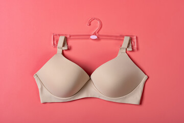 outside of a beige bra for women on a pink background