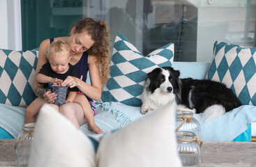 Mother eating snacks with baby son on patio sofa