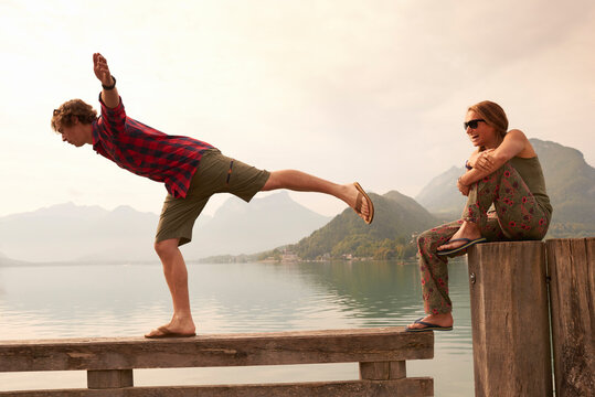 Young couple balancing on pier, Lake Annecy, Annecy, Rhone-Alpes, France