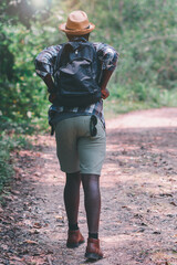 African man traveler walking in the forest with backpack