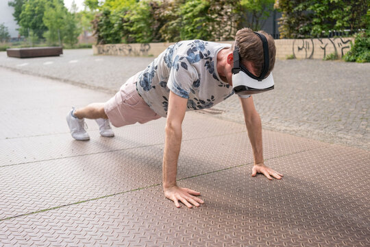 Man in push up position using virtual reality goggles, Berlin, Germany