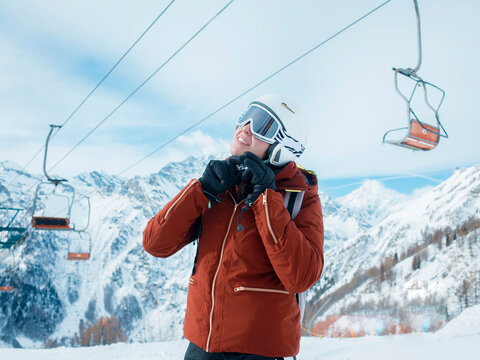 Young woman skier fastening helmet in snow covered landscape, Alpe Ciamporino, Piemonte, Italy