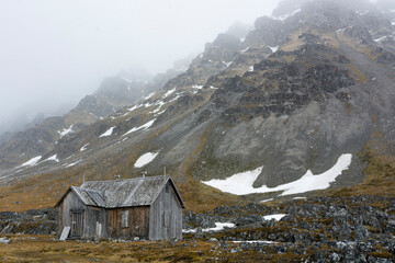 Abandoned cabin in mountain landscape. Varsolbukta, Bellsund bay, Van Mijenfjorden, Spitsbergen, Svalbard, Norway
