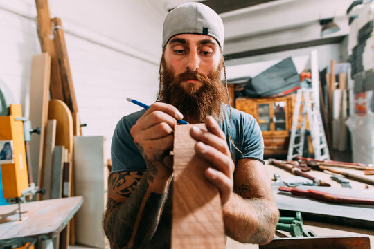 Axe maker measuring wood for axe handle in workshop