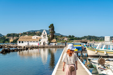 Tourist walking on bridge leading to Vlacherna Monastery, island on background, Corfu, Kerkira, Greece