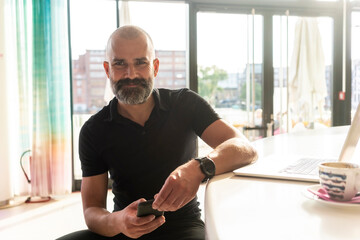 Man using mobile phone in office on sunny day