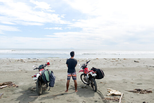 Motorcyclist carrying surfboard on sandy beach, Abulug, Cagayan, Philippines