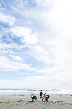 Motorcyclist carrying surfboard on sandy beach, Abulug, Cagayan, Philippines