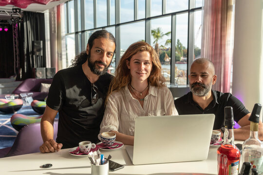 Group of three entrepreneurs using laptop and having coffee in office