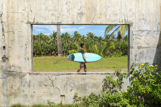 Surfer seen through window of abandoned building, Abulug, Cagayan, Philippines