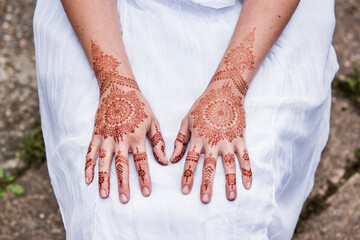 Woman in white dress with henna tattoo on hands