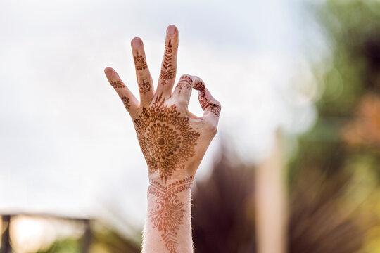 Hand with henna tattoo making gesture