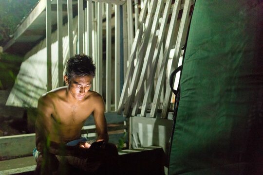 Man texting by wooden building, Abulug, Cagayan, Philippines