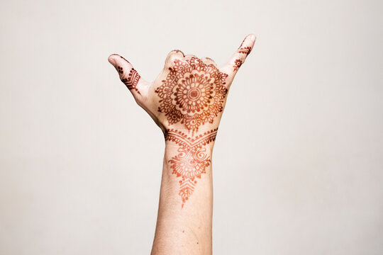 Hand with henna tattoo making gesture