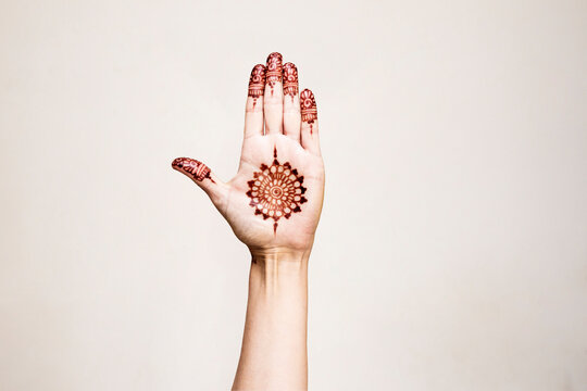Hand with henna tattoo making gesture
