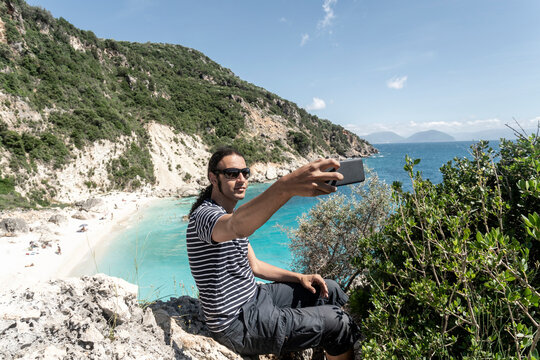 Man taking selfie on cliff top, Lefkada Island, Levkas, Greece