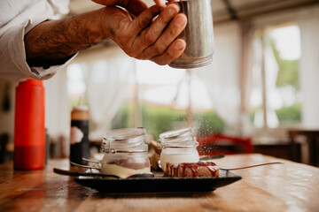 Chef sprinkling icing sugar on dessert