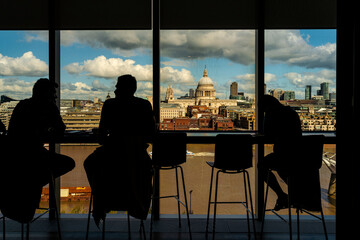 Silhouette of people having conversation by glass window, St Paul's Cathedral in background, City of London, UK
